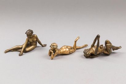 null Trois sujets en bronze ciselé et doré représentants des femmes nues assises.
(Accident...