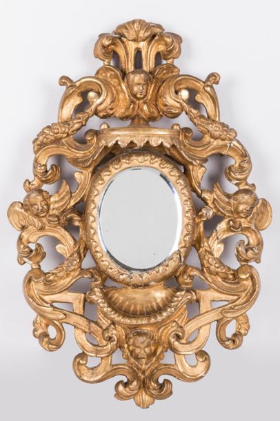 null Petit miroir en bois sculpté et doré à vu ovale, bordé d 'un improtant décor...