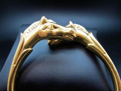 null HERMES. Bracelet jonc ouvert en métal plaqué or à motif de deux têtes de cheval....