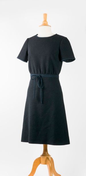 CHANEL, Uniform 

Petite robe noire en tweed ceinturée à la taille par un cordon...