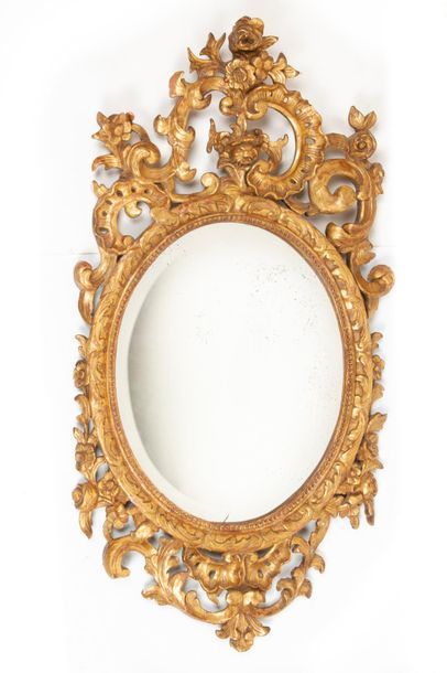 XIXème siècle Miroir ovale biseauté à cadre en bois sculpté doré ajouré à décor asymétrique...