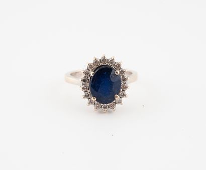  White gold (750) ring set with a faceted oval glass field sapphire and small diamonds...