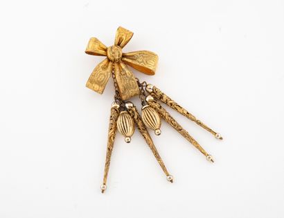 Yves Saint LAURENT Pendant en métal doré guilloché figurant un noeud de ruban retenant...