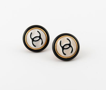 CHANEL 
A pair of gilt metal and black composition ear clips centered with the brand's...