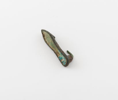 null Petite fibule en forme de de semelle en bronze. 

Long. : 4 cm. 

Epingle manquante.

Usures...