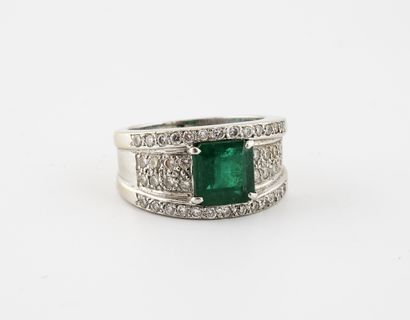  White gold (750) band ring centered on a claw-set emerald in a setting of brilliant-cut...