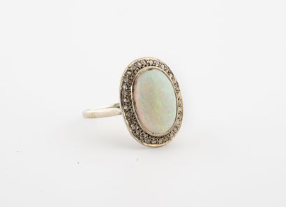 null A white gold (750) ring centered on a cabochon of white opal in a closed setting,...