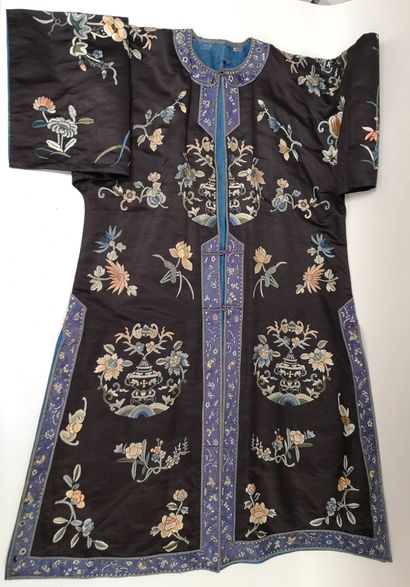 CHINE, Début XXème siècle Tunique longue en soie noire brodée de motifs floraux polychromes.

H....