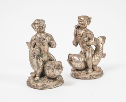 CHINE, XXème siècle - Girl and boy each riding a carp. 

Statuettes in silver plated...