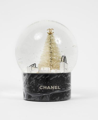 CHANEL Snow globe with a snow-covered Christmas tree under a globe and surrounded...