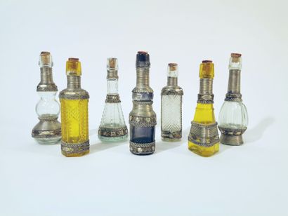  Set of 7 clear, smoked and yellow colored glass bottles with metal mountings decorated...