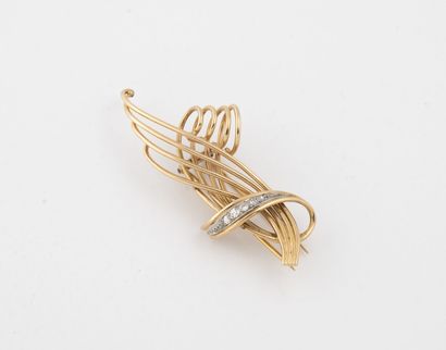 null Yellow gold (750) filigree lapel clip stylizing two leaves with a link punctuated...