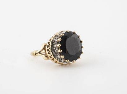 null 
Yellow gold (750) ring centered on a round faceted dark sapphire in a claw...