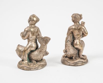 CHINE, XXème siècle - Girl and boy riding a carp each. 

Statuettes in silver plated...
