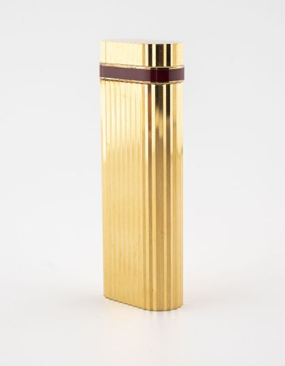 CARTIER, MUST Briquet de poche en métal doré rainuré, bordure d'émail rouge sur le...