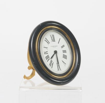 CARTIER Paris Oval alarm clock in gilt metal, the bezel enamelled black.

White enamelled...