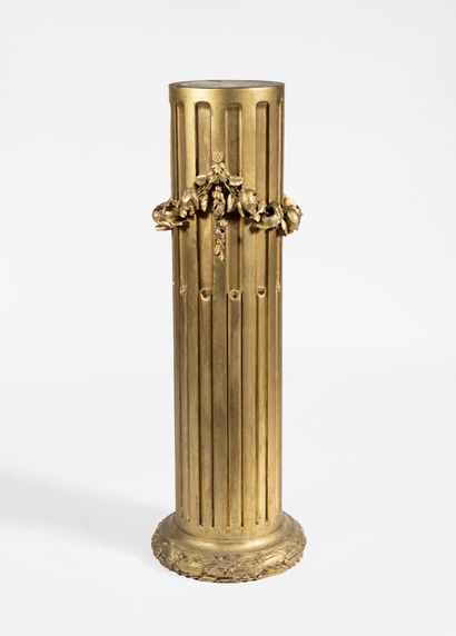 A gold patinated wood column with curved...