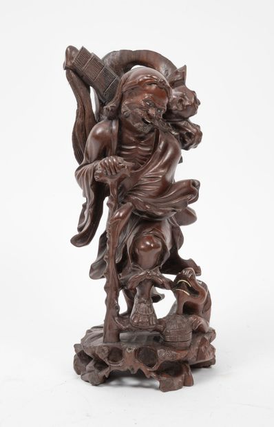 CHINE, XXème siècle - Seated man petting a dog in red wood.

Base in blackened wood.

Total...
