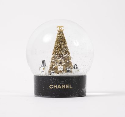CHANEL Snow globe with a glittering golden tree surrounded by boxes and gift bags...