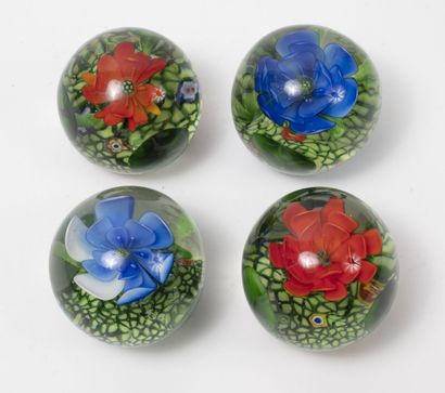 Belgique (?) Quatre boules presse-papiers en verre incolore à décor de fleurs (bleue,...