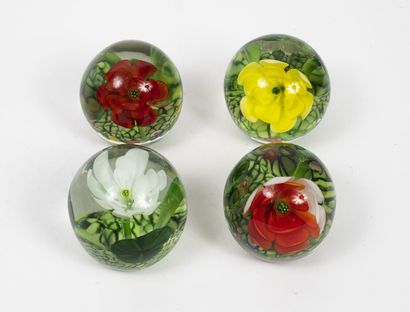 BELGIQUE (?) Quatre boules presse-papiers en verre incolore à décor de fleurs (jaune,...