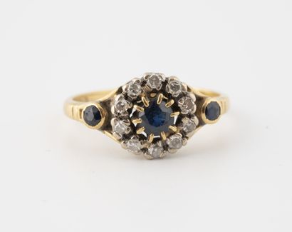 null Yellow gold (750) ring centered on a round sapphire in a claw-set setting surrounded...