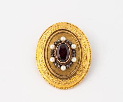 null Yellow gold (750) medallion brooch centered on an oval faceted garnet in a setting...