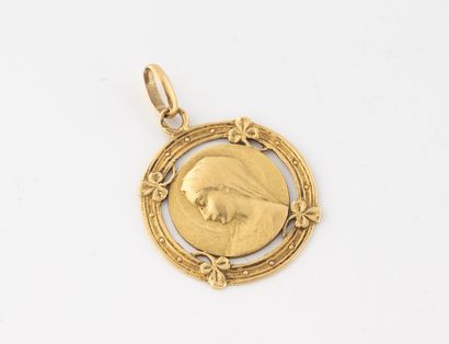 null Médaille ronde en or jaune (750) figurant la Vierge et à décor fleuri ajouré.
Dos...