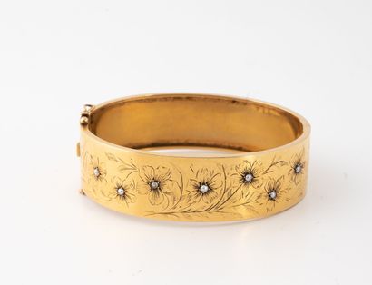null Bracelet rigide ouvrant en or jaune (750) à décor ciselé de fleurs ponctuées...