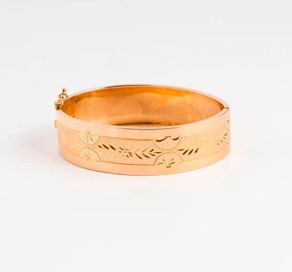 null Bracelet rigide en or jaune (750) ouvrant à décor ciselé de feuillages sur fond...
