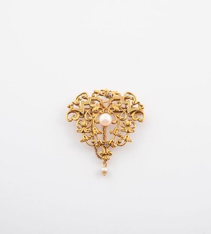 null Broche en or jaune (750) de forme volute ajourée et centrée d'une perle de culture...