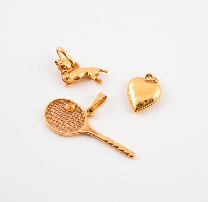 null Trois pendentifs en or jaune (750) figurant une raquette, un coeur et un chien....