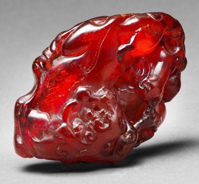 CHINE - XVIIIe siècle 
Carved amber group, a lying chimera holding a branch in its...