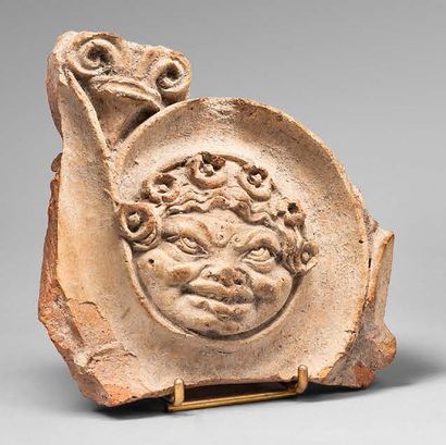 null Fragment of an ornamental plate showing a grinning gorgoneion in a scroll decoration.
Beige...