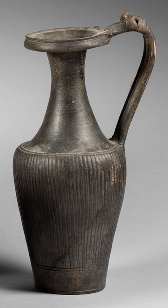 null Black-glazed enochoe with a fluted body, the handle of which is decorated with...