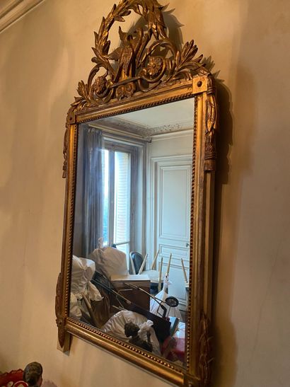 null Carved and gilded wood mirror surmounted by a leafy pediment with a couple of...