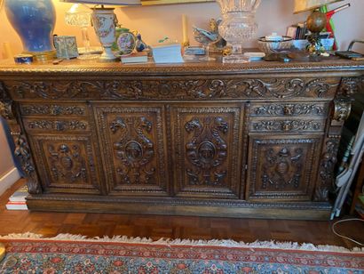 null Low sideboard in richly carved oak opening to a flap, four drawers and four...