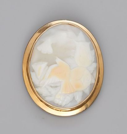   Broche ovale en or jaune 750°/00(18K) , sertie d'un camée coquille à décor de fleurs....