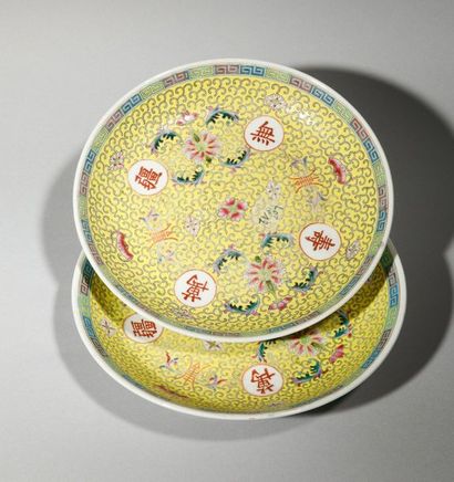 null Deux assiettes en porcelaine à décor floral et idéogramme sur fond jaune. Chine,...