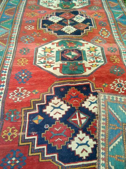 null Tapis Kazac à motifs géométriques sur fond rouge. Usures. 310 x 190 cm