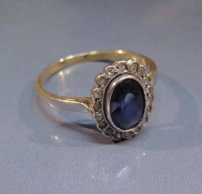 null Bague en or deux tons, centrée d'une pierre bleue (synthèse) entourage de diamants...