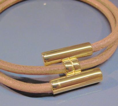 null HERMES Bracelet tourbillon en métal doré et cuir naturel. Signé. Pochette.