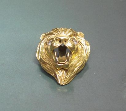   Pendentif tête de lion ciselé en or jaune 750°/00, les yeux sertis de diamants...