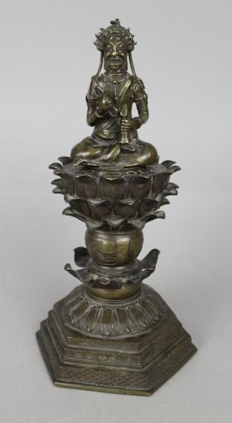 null Bouddha en bronze patine en position assis et tenant des instruments sur un...