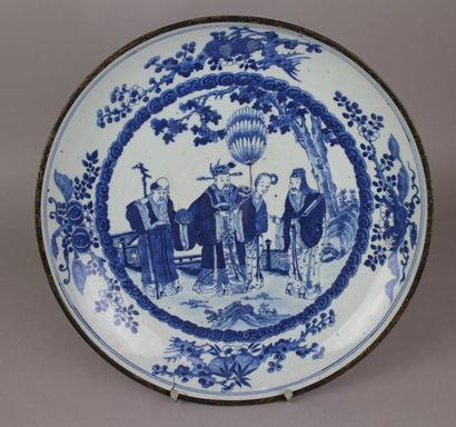 null Chine. Grand plat rond en porcelaine à décor blanc bleu d’une scène de dignitaires...