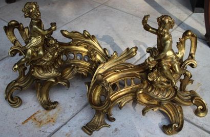 null Paire de chenets en bronze doré Louis XV à décor rocaille surmontés d’enfants....
