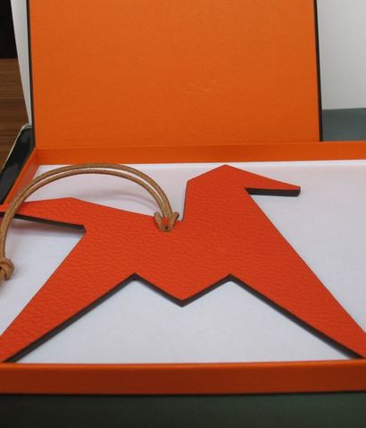 HERMES Bijou de sac en cuir orange réversible vert dessinant un cheval. Signé, sans...