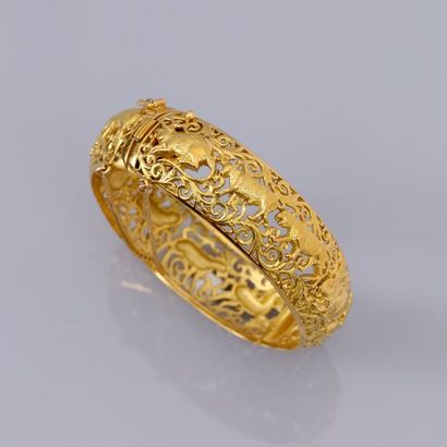  Bracelet rigide bombé en or jaune 750°/00, à décor ajouré des 12 signes de l'horoscope...