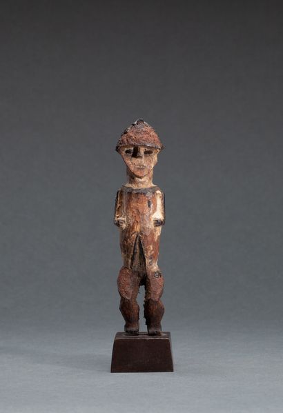  Statuette 
présentant un personnage debout, les genoux fléchis et le visage triangulaire,...
