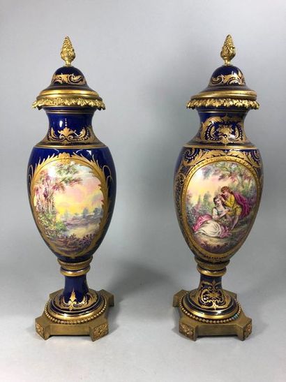 null Paire de vases en porcelaire dans le goût de Sèvres, à fond bleu, décor de scène...
